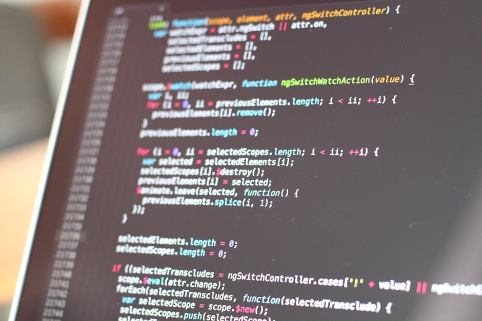 A close-up image of a computer screen displaying lines of colorful programming code, including HTML, CSS, and JavaScript syntax. The code is slightly blurred, with visible elements such as brackets, f